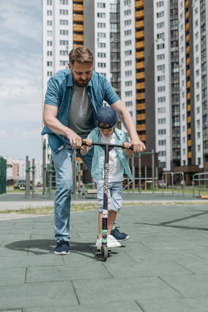 A Man Teaching His Son How to Use a Scooter